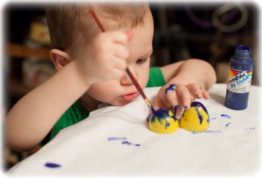 Two year old Grandson paints an egg. 