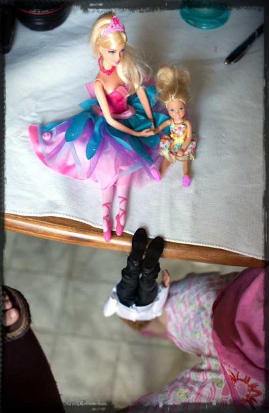 Barbie, Chelsea and Ken play Triopoly but Ken gets grumpy because he lost so he hangs from the table by his feet because he is grumpy.