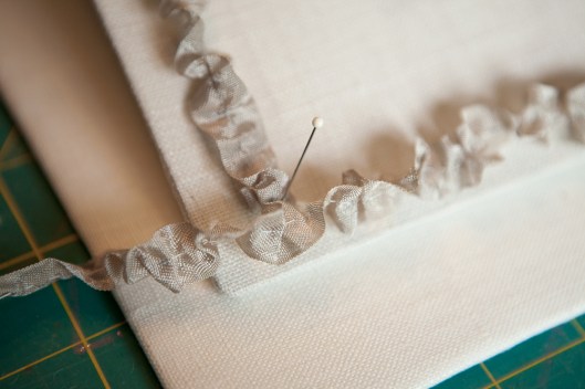 Seam binding tape is gathered down the middle and the pinned to the cover to check for size and adjust ruffles.
