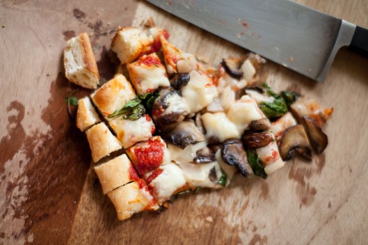 Warm piece of homemade Spinach Mushroom Onion pizza, cut into 3/4" squares.