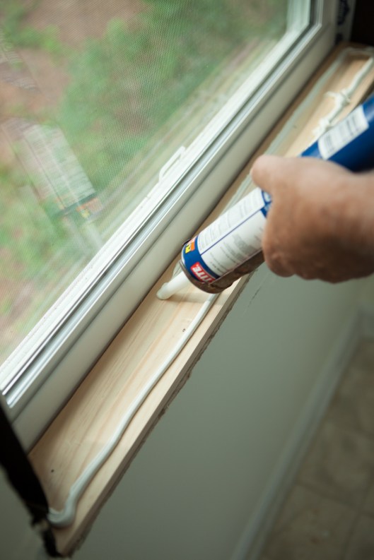 Squeezing out the heavy-duty construction adhesive to place the sills.