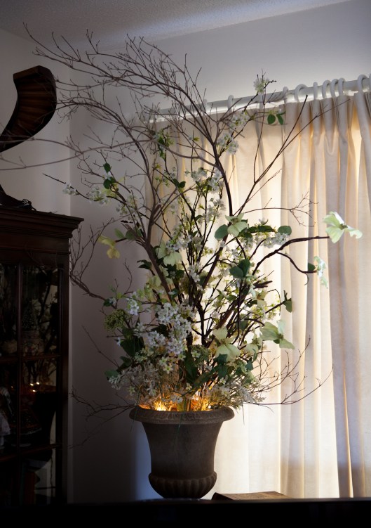 The same bare branches now share the space with artificial dogwood and greens. The lights were taken off the branches and placed in the vase for ambience.