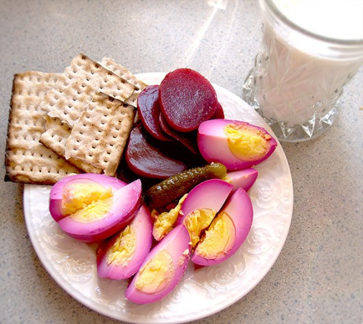 Two pickled eggs with beets, a sweet pickle and matzoh. 