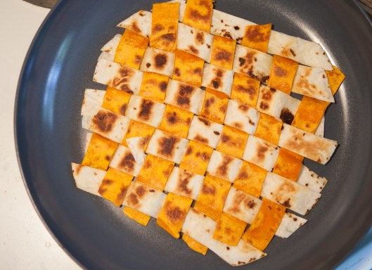 The woven tortilla mat is lightly toasted on both sides over medium heat in a skillet.