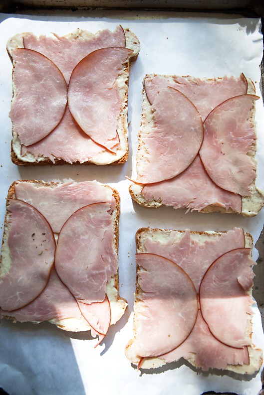 Tear two round ham slices in half to fit a square piece of bread.